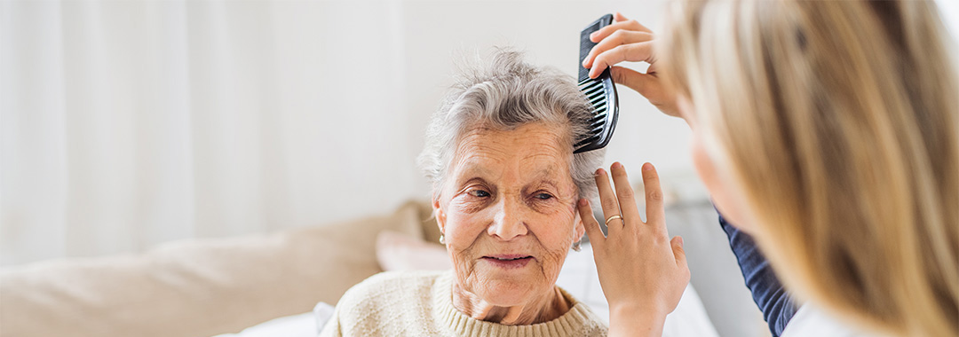 Healthcare worker combing the hair of a senior woman.